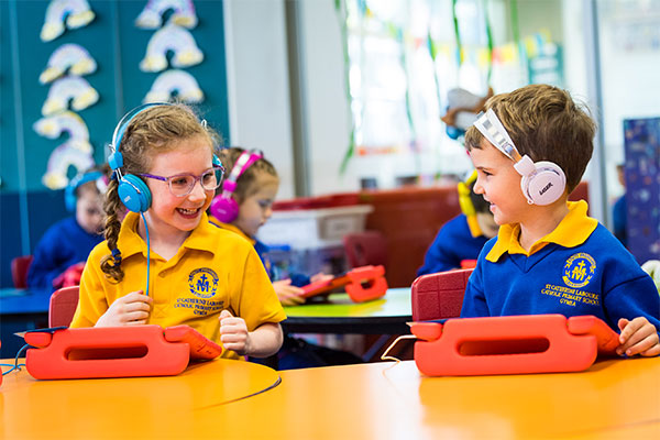 Students smiling and using tablets at St Catherine Labouré Catholic Primary School Gymea
